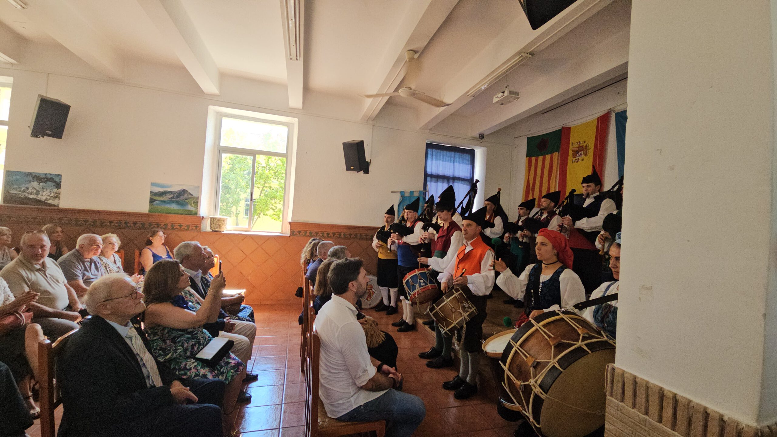 Gaiteros y tamborileros interpretan música ante el público en el salón del Centro Asturiano.