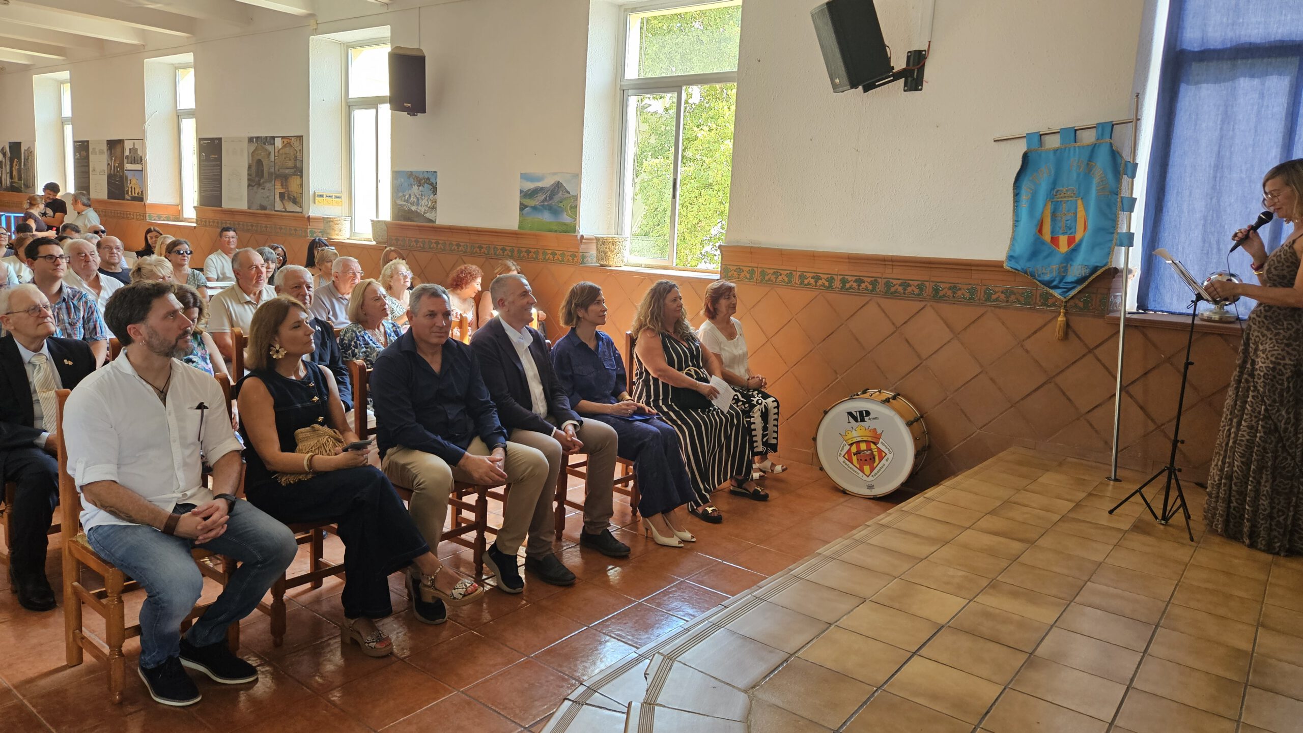 Asistentes y representantes institucionales escuchan una intervención en el salón del Centro Asturiano.